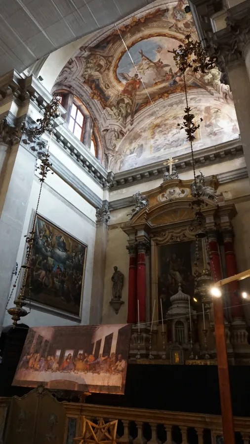 Interior of a church with frescoed vaulted ceilings, an ornate altar, and religious paintings