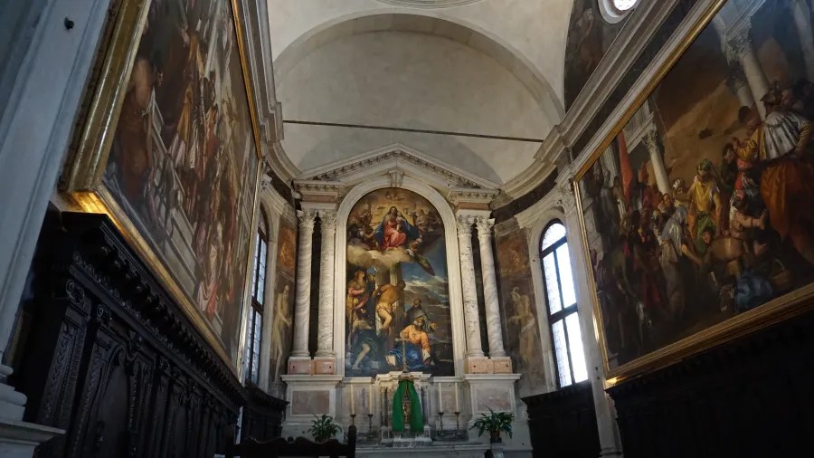 Interior of a chapel with large religious paintings on the walls and main altar.