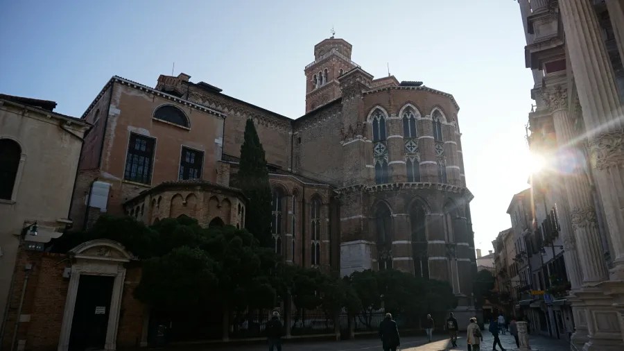 Large brick cathedral with a bell tower and gothic windows in a sunny city square