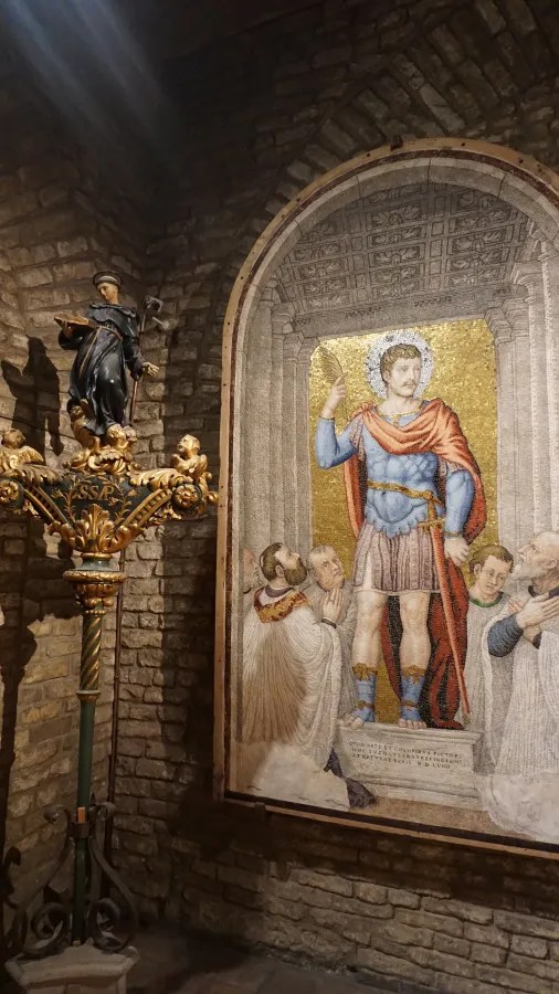 20221015_1_Italien_Venedig (50) Mosaic of a soldier saint with Latin text and a saint statue on a gilded stand labeled SSP.