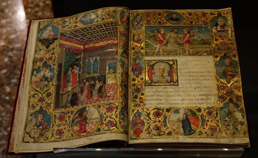 20221015_1_Italien_Venedig (53) Open illuminated manuscript with religious miniatures and text: Quanto e la gloria de la sanctissima trinita nanno con magna pieta e nel modo che l'anima nostra obligata na natura la qual esser nati ala imagine e naltre de questo mondo quanto ha ad esse o d'un dolce mentore et redemptore n'ro. Et