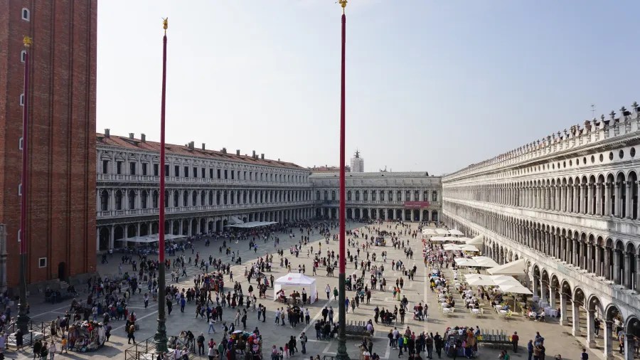 20221015_1_Italien_Venedig (65) Crowded St. Mark's Square in Venice with historic buildings and tall flagpoles.