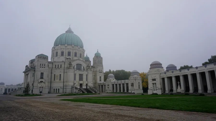 Grand white domed building with a green dome shrouded in morning fog