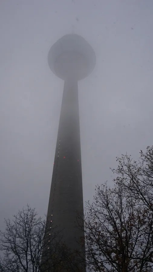 Tall concrete tower with a circular top partially hidden by thick, grey fog.
