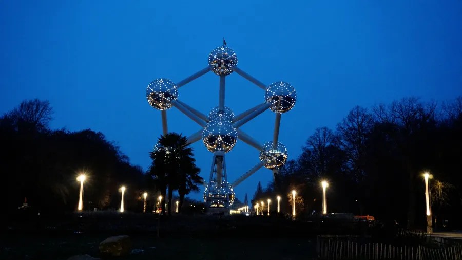 The illuminated Atomium structure in Brussels against a dark blue evening sky.