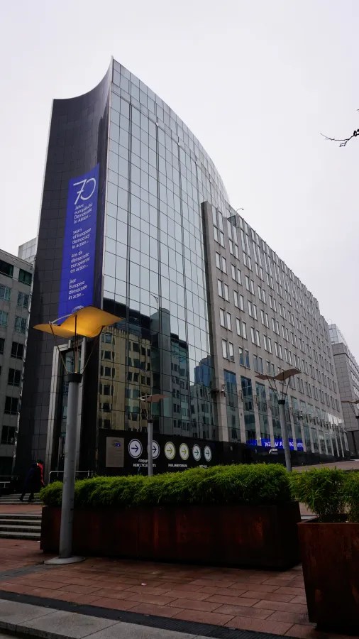 Modern glass building with a blue banner reading: 70 Jahre europäische Demokratie in Aktion... years of European democracy in action... ans de démocratie européenne en action... jaar Europese democratie in actie...