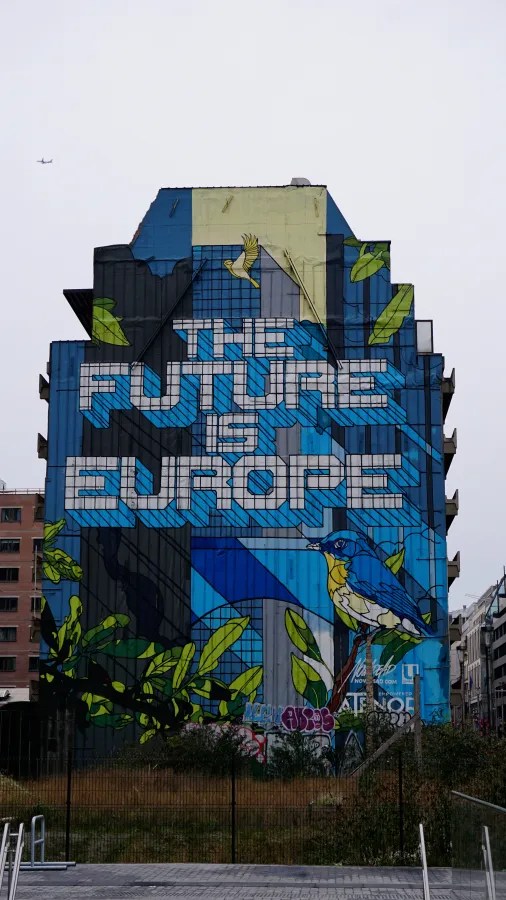 A mural on a building reading THE FUTURE IS EUROPE, with birds and green leaves.
