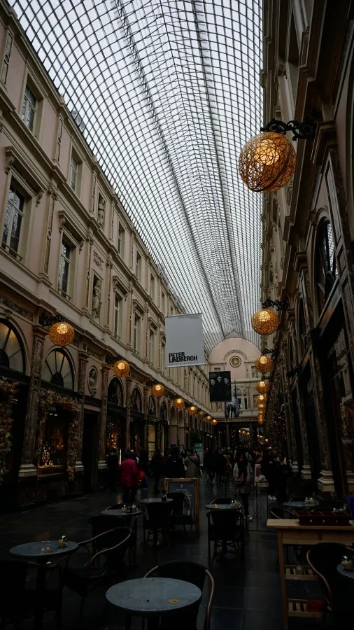 Neoclassical shopping gallery with a vaulted glass ceiling and glowing orange globe-shaped lanterns.