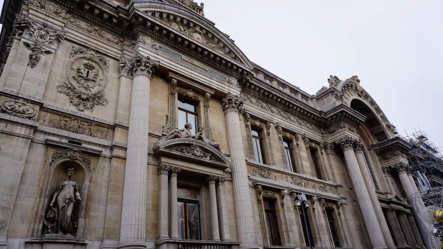 Grand neoclassical facade with a large arched entrance, Corinthian columns, and ornate sculptures.