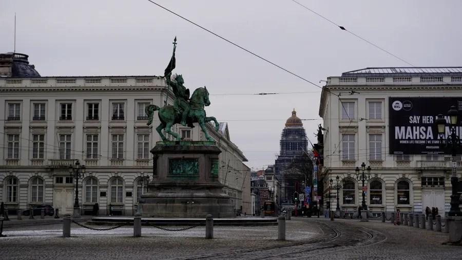 Statue of Godfrey of Bouillon in Brussels with a billboard reading 'Say Her Name Mahsa Amini'.