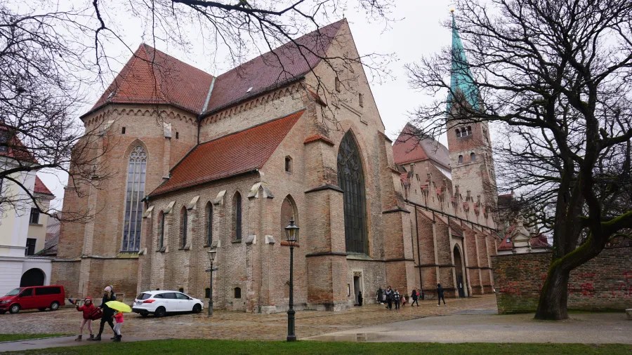 Large brick Gothic cathedral with a red-tiled roof and a tall green-tipped spire.