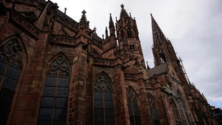 Low-angle view of a red sandstone Gothic cathedral with intricate spires under a cloudy sky