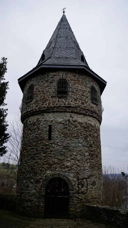 A round stone tower with a steep conical roof and an arched entrance.