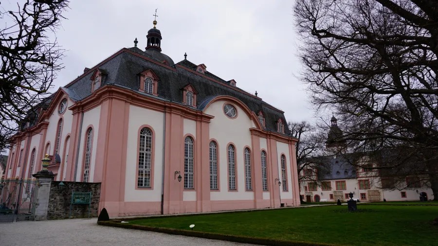 Pink and white Baroque-style building with tall arched windows and a gray mansard roof.