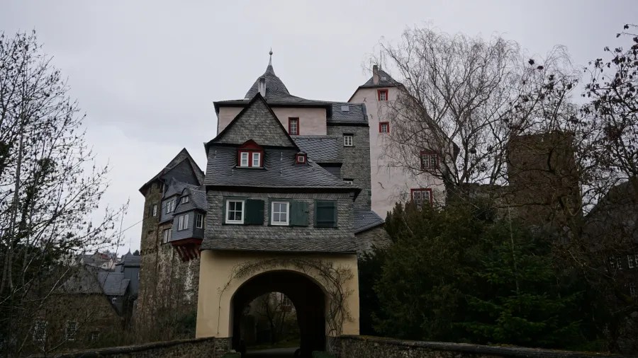 Historic multi-tiered building with slate roofs and an arched stone gateway passage.