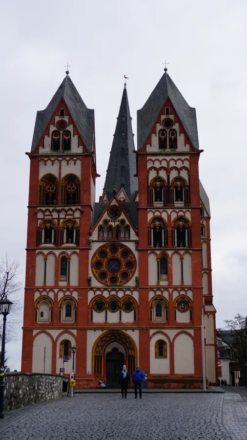 The red and white Limburg Cathedral with its prominent Romanesque towers and central rose window.