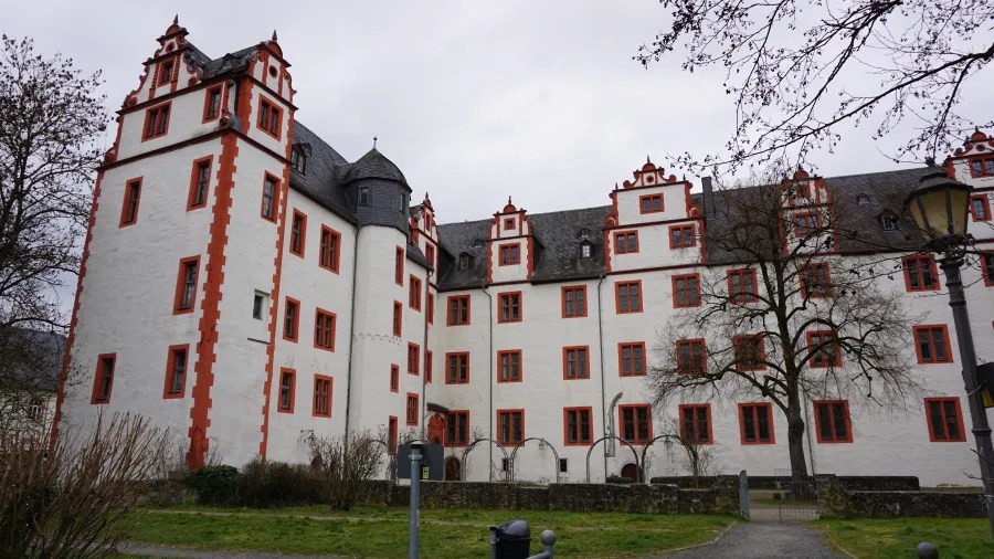 Historic white building with red trim, ornate gables, and a round tower