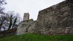Ancient stone fortress walls and a square tower under an overcast sky.