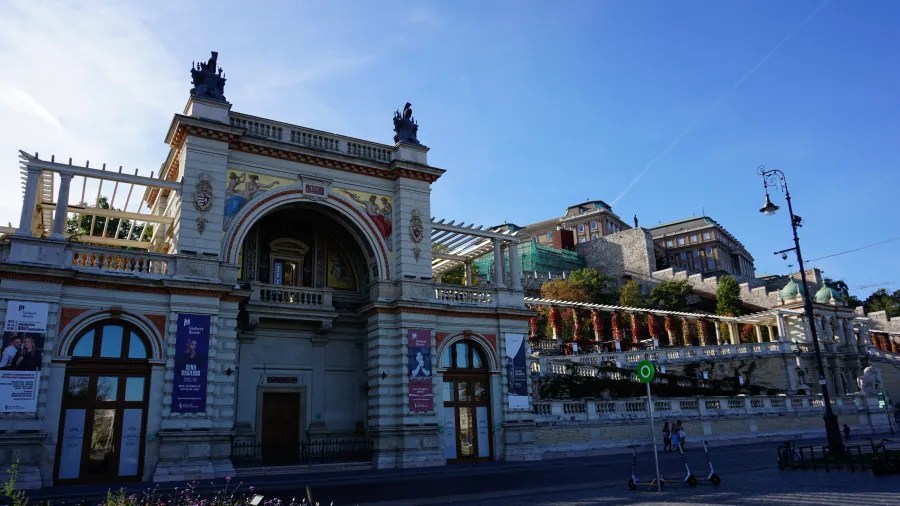 Ornate Várkert Bazár building in Budapest with Buda Castle visible on the hill behind it.