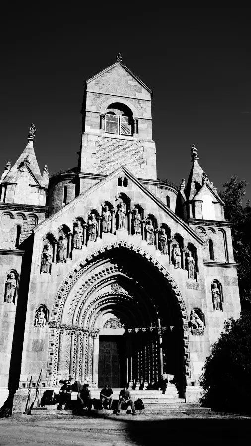 Black and white view of an ornate stone church entrance with statues and a tower