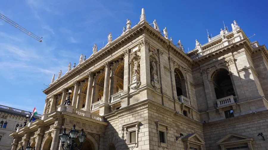 Ornate facade of the Hungarian State Opera House with numerous statues under a clear blue sky