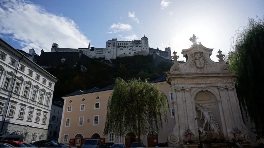 Hohensalzburg Fortress on a hill overlooking a square with buildings and a stone fountain in Salzburg