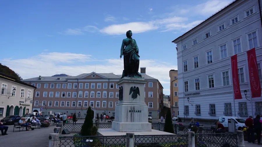 Bronze statue of Wolfgang Amadeus Mozart on a white pedestal in a public square