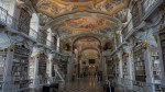 Ornate baroque library featuring white and gold bookshelves and detailed ceiling frescoes
