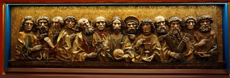 Gilded high-relief wood carving depicting Christ and the twelve apostles with their symbolic attributes.
