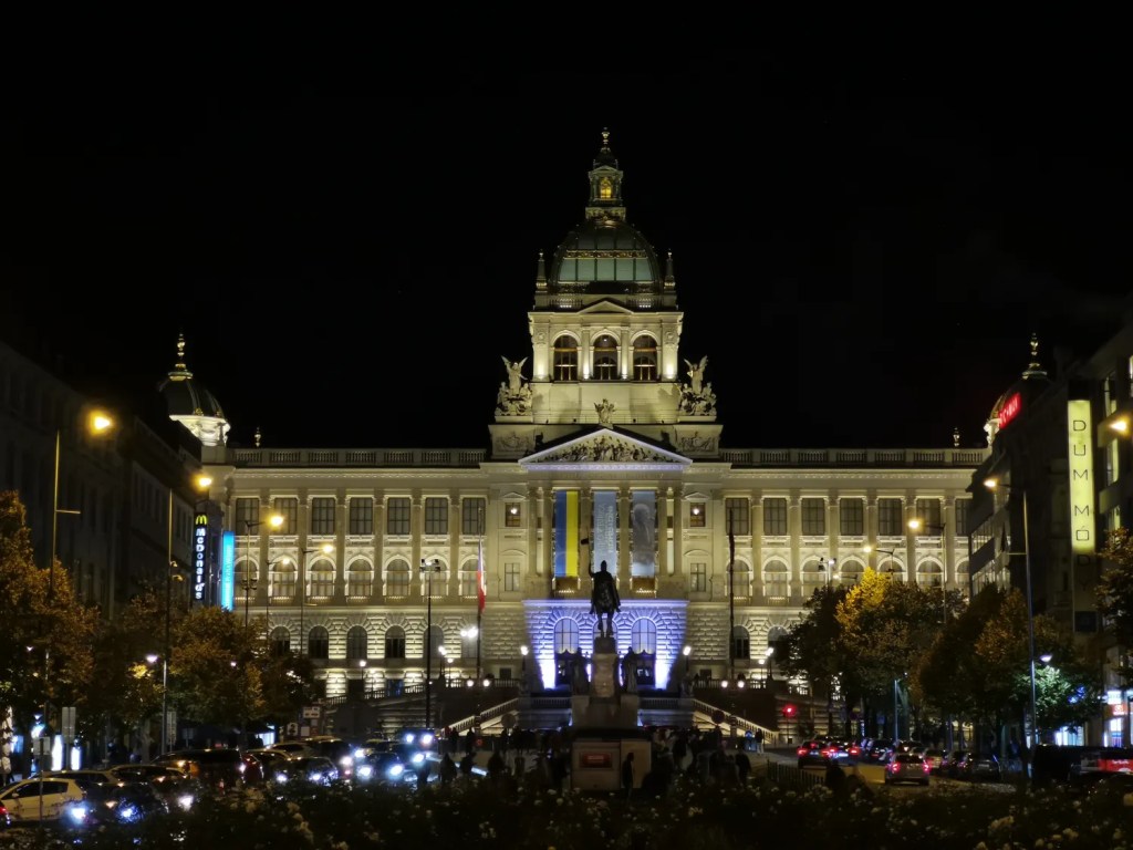 Illuminated National Museum in Prague at night with McDonald's and Dům módy signs visible.
