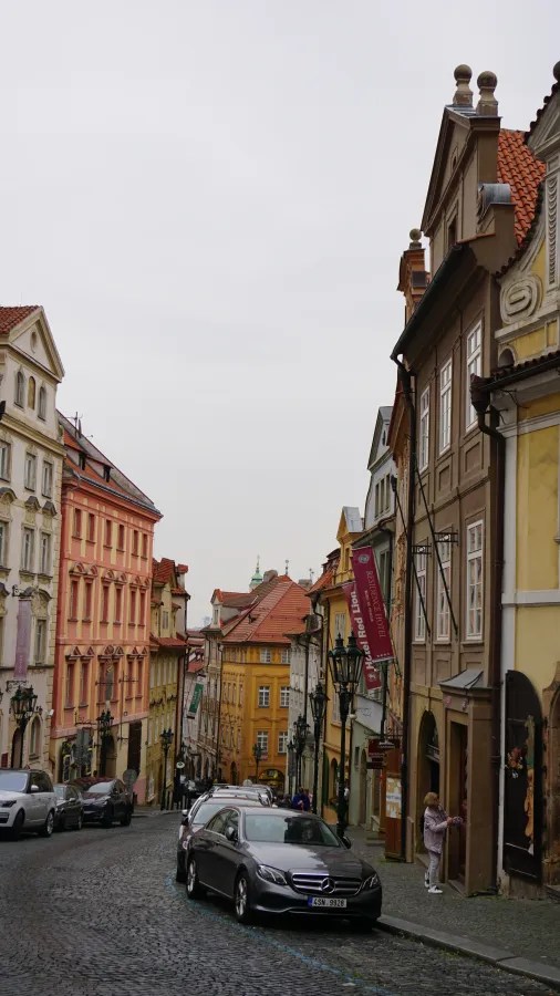 A narrow cobblestone street lined with historic, colorful European buildings including the Hotel Red Lion