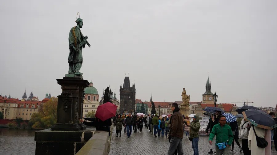 20221021_Tschechien_Prag (204) Crowds with umbrellas crossing the Charles Bridge in Prague on an overcast day.