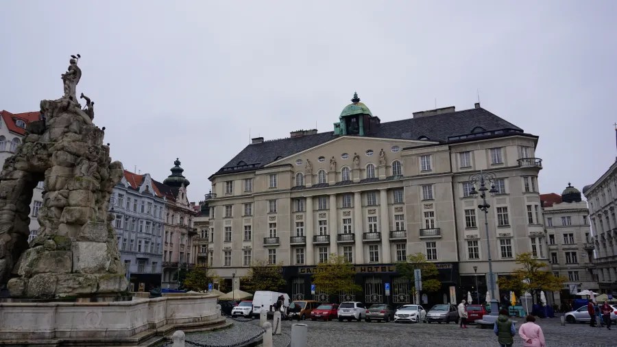 The rocky Parnas Fountain and Grandezza Hotel in a city square under an overcast sky.