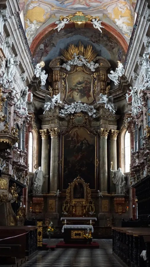 The grand, ornate Baroque altar of a church with gold accents and white sculptures.