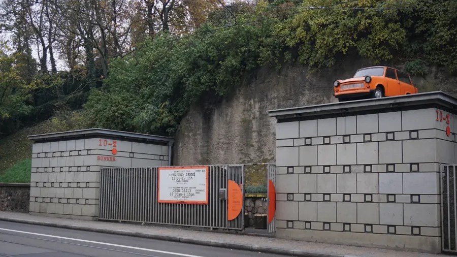 Entrance to the 10-Z BUNKER with an orange car on the roof and a sign listing opening hours.