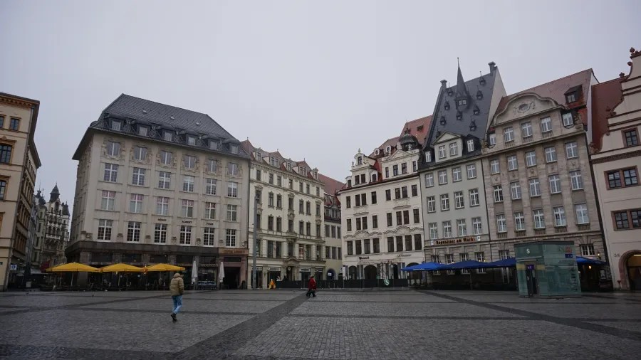 Cobblestone city square surrounded by historic European buildings with ornate facades and outdoor cafes.