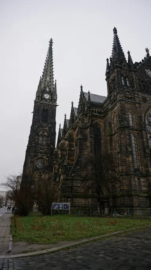 Gothic revival church with a tall clock tower and intricate dark stone architecture.