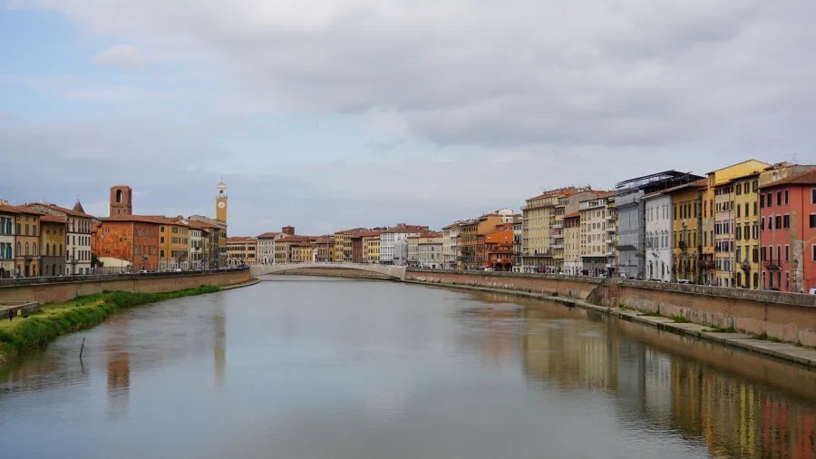 20230420_Italien_Toskana_Pisa (3) River flowing through a city with rows of historic buildings on both banks under cloudy sky