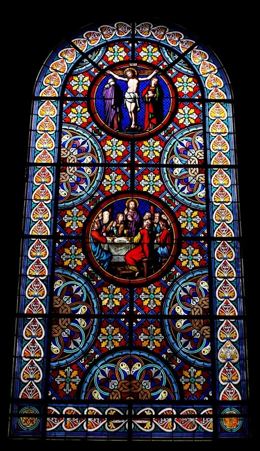 Ornate stained glass window featuring circular panels depicting the Crucifixion and the Last Supper.