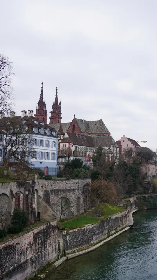 European old town cityscape featuring a twin-spired cathedral overlooking a river from high stone walls