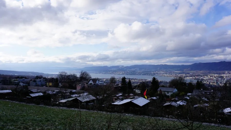 Scenic view of a town nestled along a lake under a dramatic, cloudy sky.