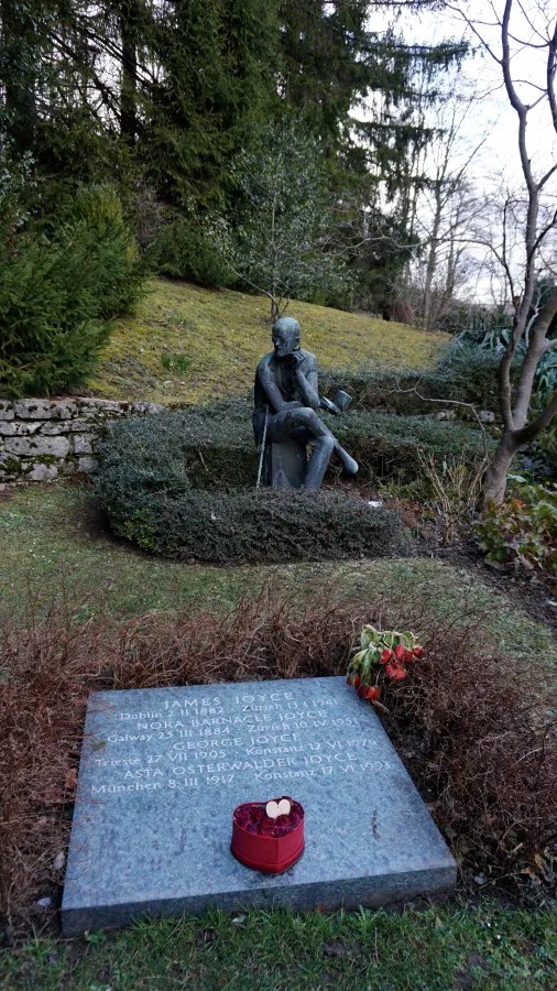 Grave of James Joyce with statue. Text: JAMES JOYCE Dublin 2 II 1882 Zürich 13 I 1941, NORA BARNACLE JOYCE Galway 25 III 1884 Zürich 10 IV 1951, GEORGE JOYCE Trieste 27 VII 1905 Konstanz 12 VI 1976, ASTA OSTERWALDER JOYCE München 8 III 1917 Konstanz 17 VI 1993.
