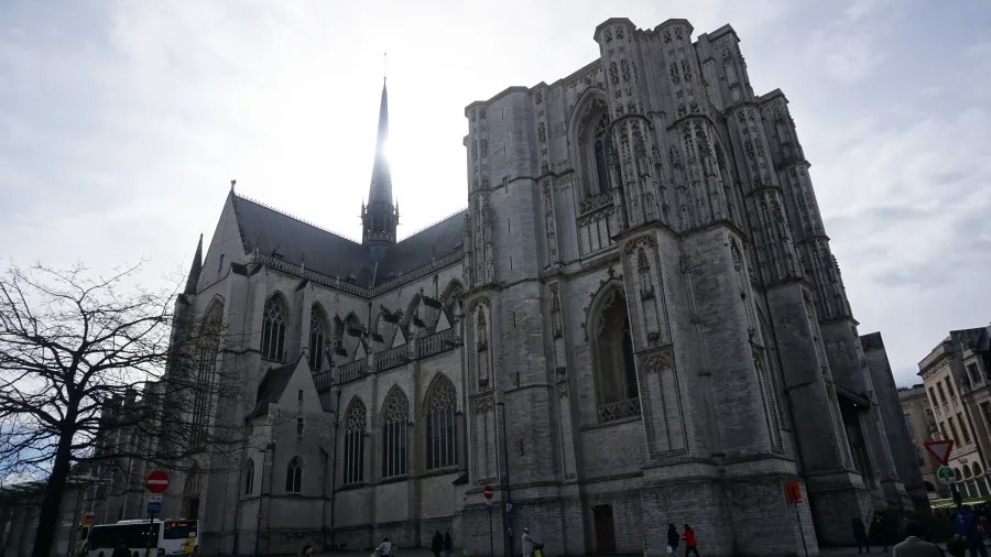 Large grey stone gothic cathedral with a tall, slender spire under an overcast sky