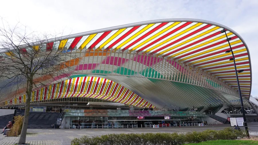 A modern architectural structure with a large white canopy and vibrant multicolored stripes underneath.