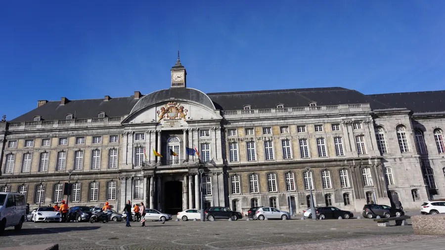 Historic building with a central clock tower and balcony overlooking a city square.