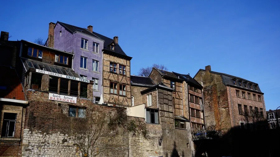 A row of historic, multi-story buildings, including one painted purple, with signs for 'CAFE - LIBRAIRIE ENTRE - TEMPS' and 'Centre Culturel BARRICADE'.