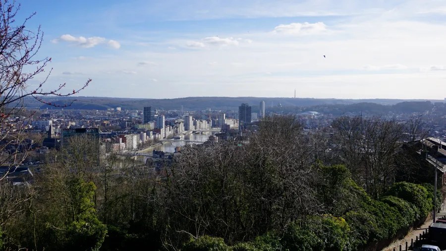 Elevated panoramic view of a city skyline along a river under a clear sky.