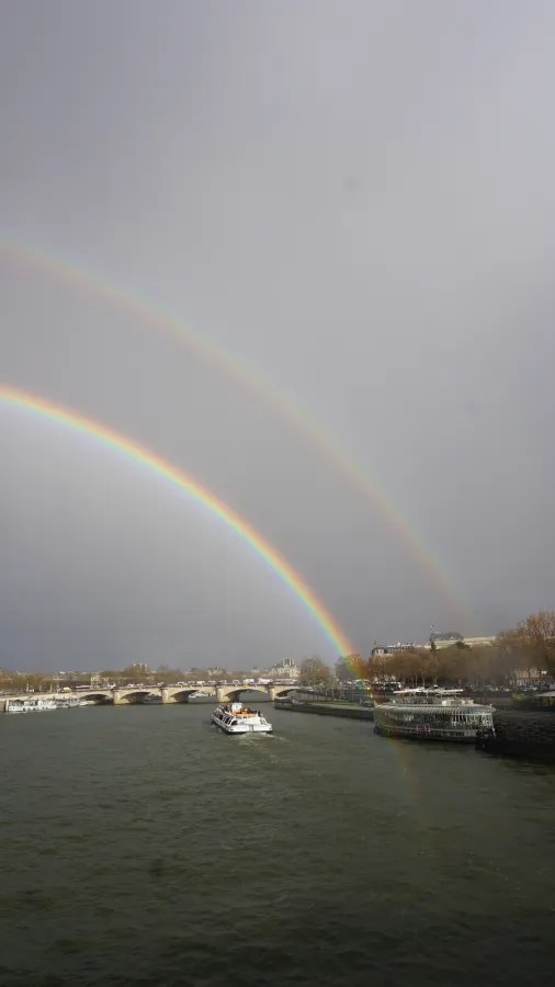 20230324_Frankreich_Paris (180) Double rainbow over a river with a boat sailing towards a bridge