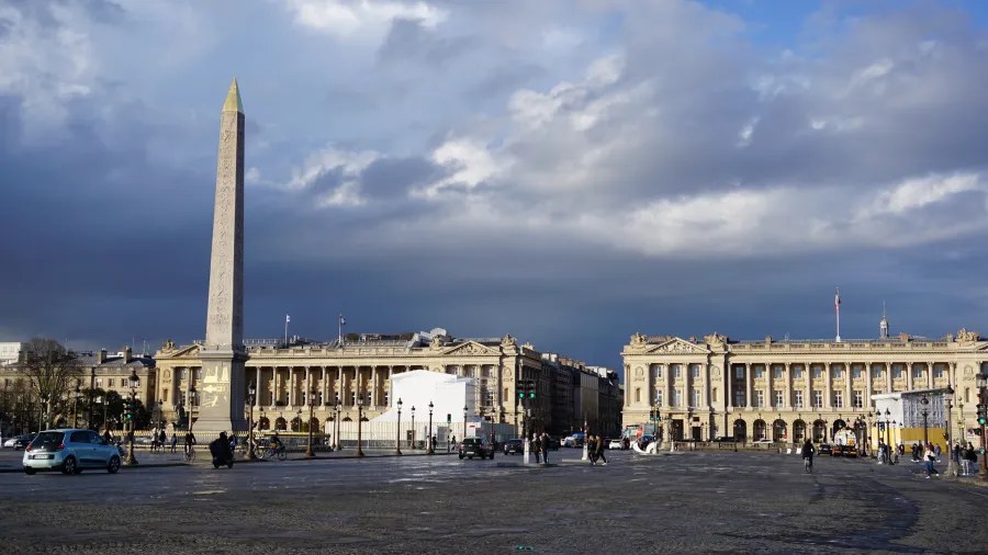 20230324_Frankreich_Paris (200) Obelisk in a large city square with classical buildings and pedestrians under a cloudy sky