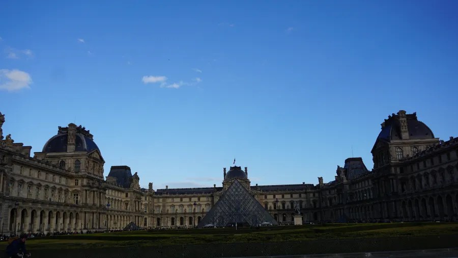 20230324_Frankreich_Paris (207) The Louvre Museum courtyard with the glass pyramid entrance and surrounding historic buildings under a clear blue sky